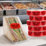 Ham and Cheese label with black text and bright red background on ham and cheese deli sandwich