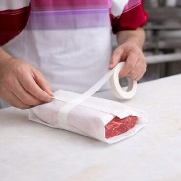 Masking Locker Tape White being used by a butcher to wrap meat in butcher paper