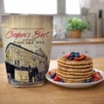 Cooper's Best Multigrain Pancake Mix next to freshly made Multigrain Pancakes