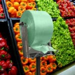 100% Recycled Produce Bags Pull N Pak shown on a rack in front of produce