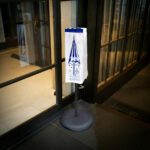 Small wet umbrella bag on a rack outside a hotel lobby