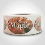 Maple Label Flavor Oval Sticker with Maple Frosted Cupcakes pictured in the background with the word Maple printed on top on roll of stickers