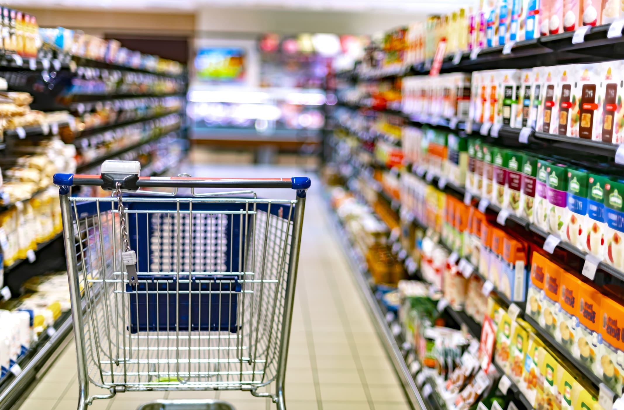 A shopping cart by a store shelf in a supermarket
