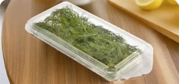 A produce container with herb in a container sitting on a table
