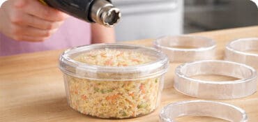 Shrink Bands on a deli container with a heat gun sealing the band