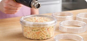 Shrink Bands on a deli container with a heat gun sealing the band