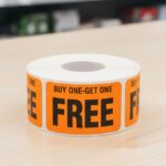 Buy one get one free sticker on a rectangle orange label with black text