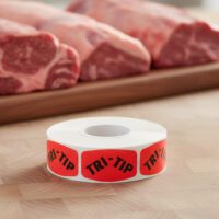 Tri-Tip Butcher sticker red identification label with black print on a roll of stickers
